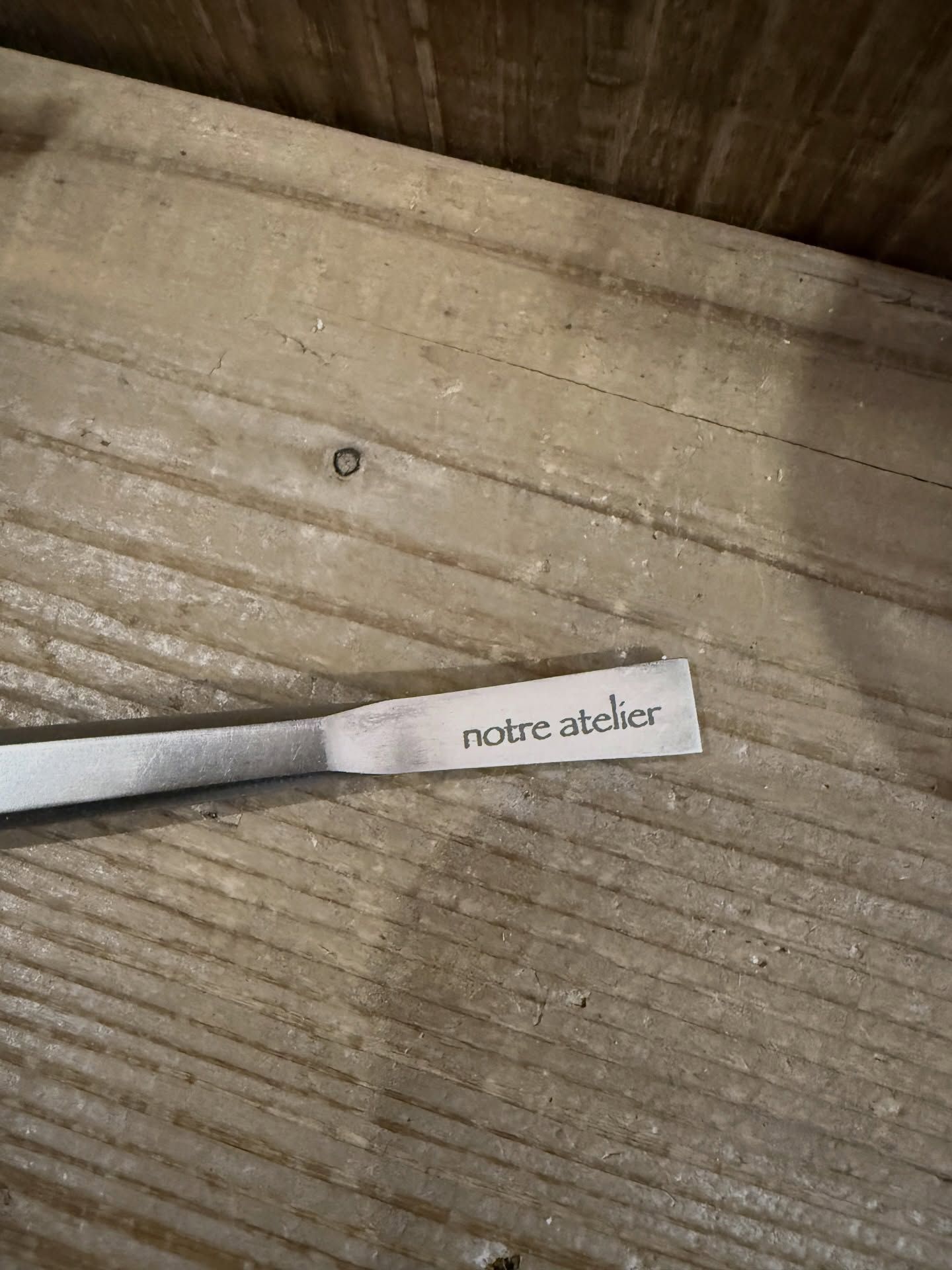 古材の板の上に置かれた、notre atelierのロゴ入りラベル